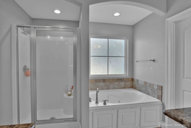 bathroom featuring a tub with jets, a stall shower, and vanity