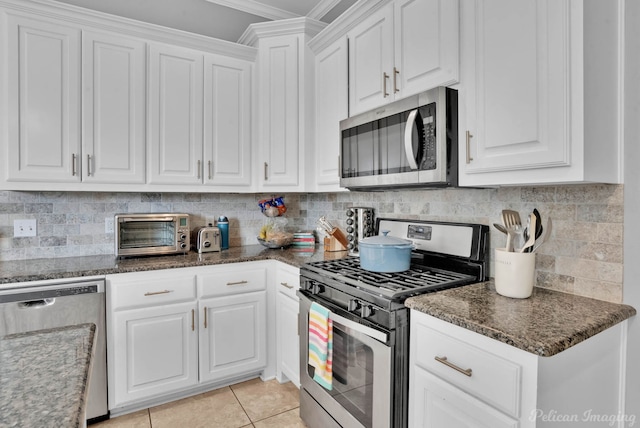 kitchen featuring stainless steel appliances, crown molding, white cabinets, and dark stone countertops