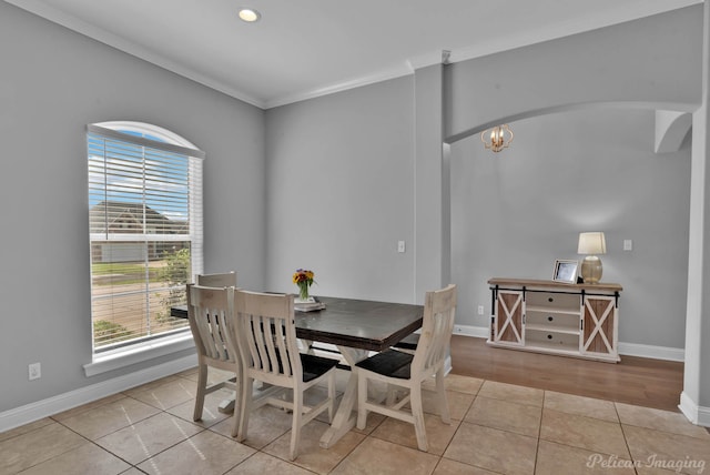 dining area with plenty of natural light, arched walkways, crown molding, baseboards, and light tile patterned floors