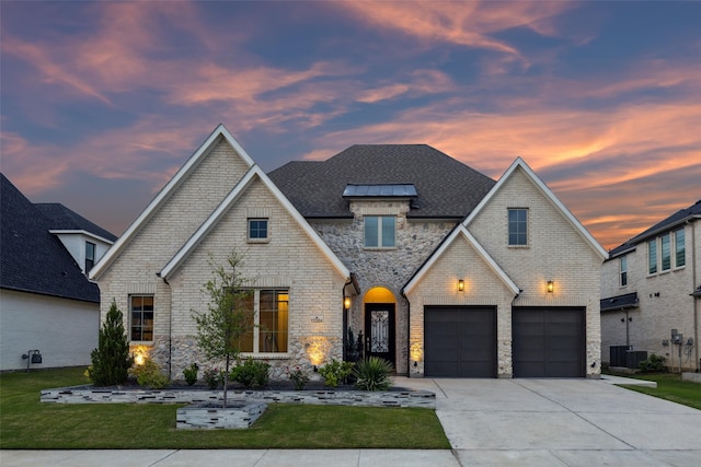 french country inspired facade featuring concrete driveway, a yard, and a garage