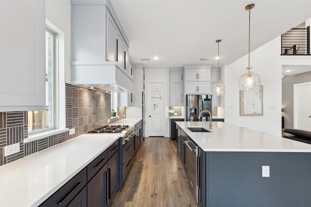kitchen featuring a sink, light countertops, decorative backsplash, stainless steel refrigerator with ice dispenser, and recessed lighting