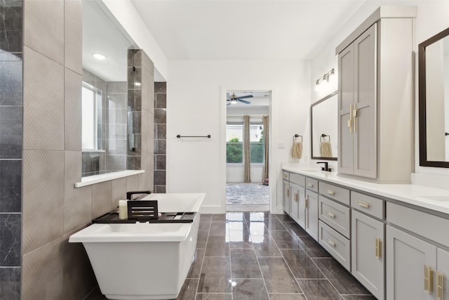 full bath with double vanity, a soaking tub, marble finish flooring, and ceiling fan