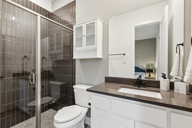 ensuite bathroom featuring toilet, a shower stall, and vanity
