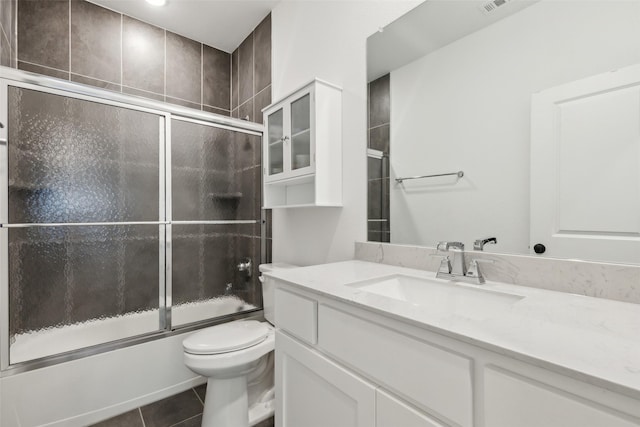 full bathroom featuring shower / bath combination with glass door, toilet, vanity, and tile patterned flooring