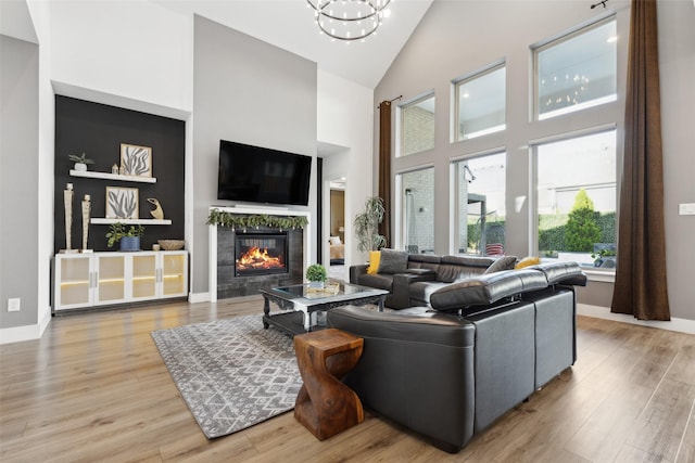 living room with high vaulted ceiling, a fireplace, wood finished floors, a chandelier, and baseboards