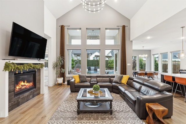 living area featuring a chandelier, light wood-style flooring, high vaulted ceiling, a fireplace, and recessed lighting