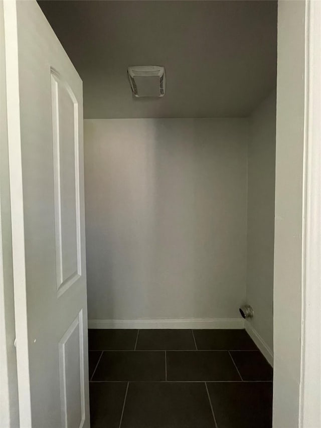 laundry area with dark tile patterned floors and baseboards