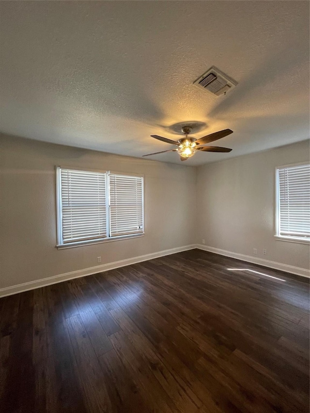 unfurnished room with dark wood-type flooring, a textured ceiling, a ceiling fan, baseboards, and plenty of natural light