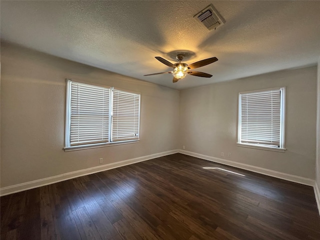 spare room with baseboards, ceiling fan, a textured ceiling, dark wood-type flooring, and healthy amount of natural light