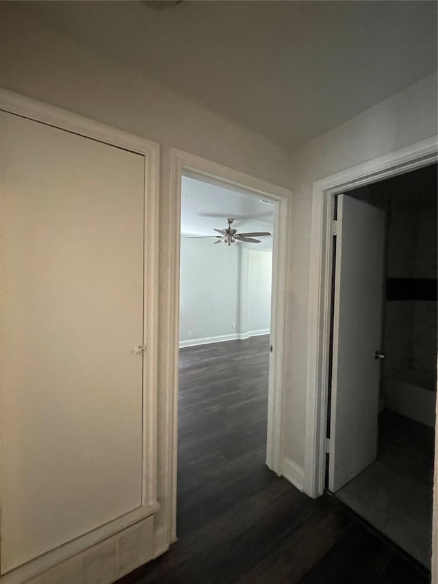 hall featuring dark wood-type flooring and baseboards