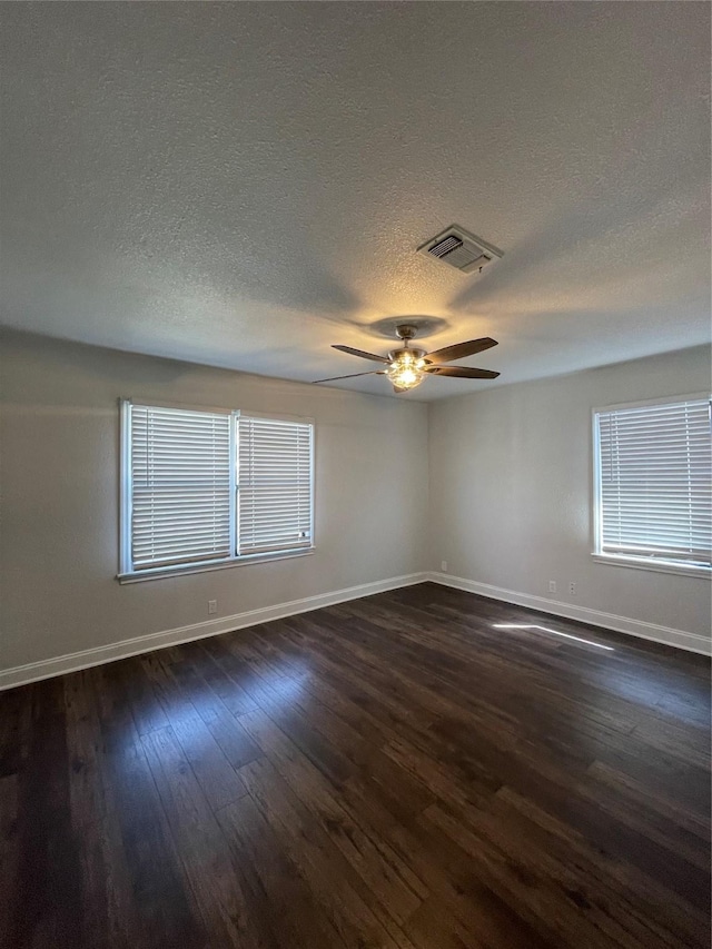 unfurnished room with baseboards, dark wood-type flooring, a textured ceiling, ceiling fan, and plenty of natural light