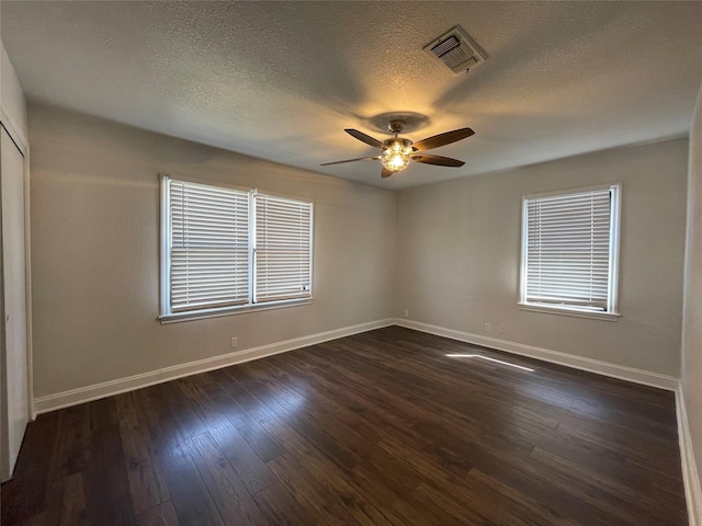 empty room with baseboards, a ceiling fan, dark wood-style flooring, and a textured ceiling