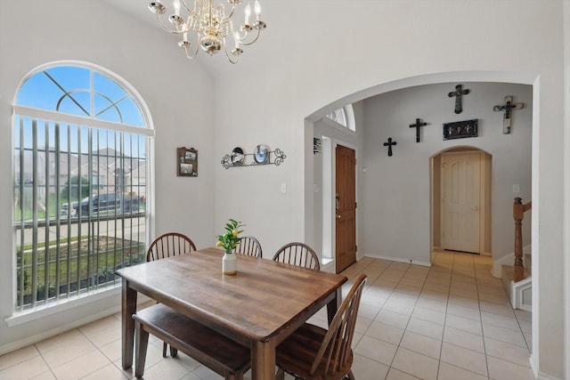 dining room with arched walkways, stairs, light tile patterned flooring, baseboards, and a chandelier