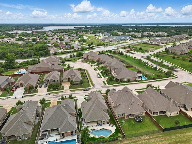 aerial perspective of suburban area featuring a pool area and a large body of water