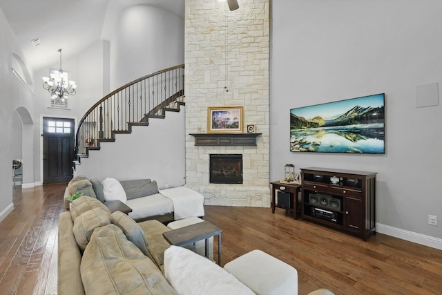living area with arched walkways, a chandelier, wood finished floors, stairs, and high vaulted ceiling