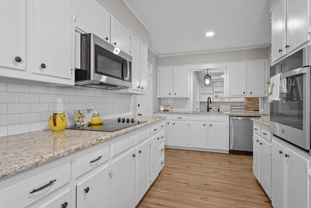3205 Creekwood Cir, Waco, TX 76710 - kitchen with stainless steel appliances, a sink, tasteful backsplash, white cabinetry, and crown molding