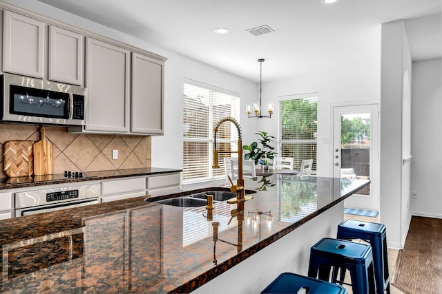 kitchen with stainless steel microwave, a sink, oven, black electric stovetop, and wood finished floors