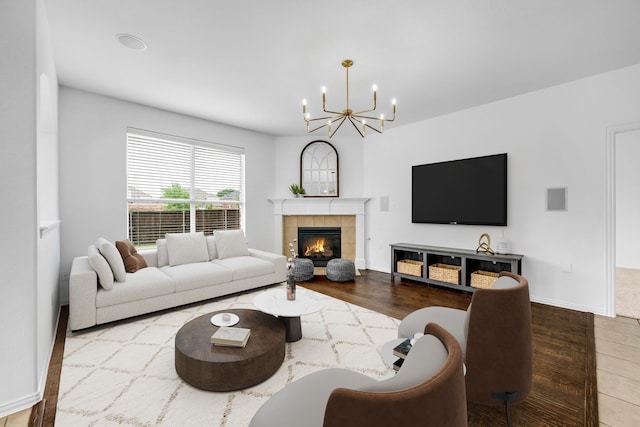 living area featuring a chandelier, a tile fireplace, and baseboards