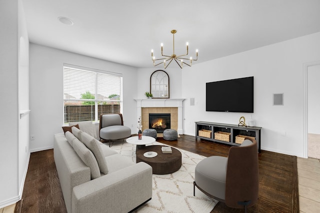 living area featuring a chandelier, a tile fireplace, wood finished floors, and baseboards