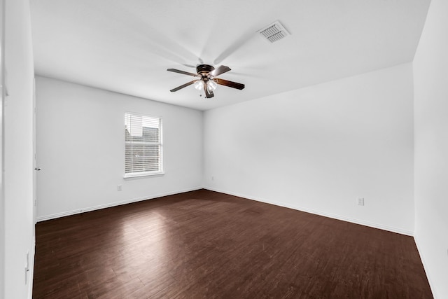 spare room featuring dark wood-style floors, a ceiling fan, and baseboards
