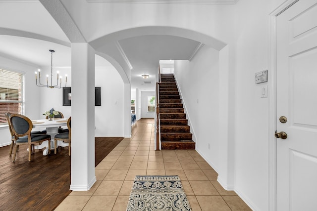 entryway featuring plenty of natural light, a chandelier, baseboards, stairway, and ornamental molding