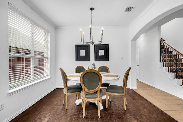 dining area with arched walkways, a chandelier, healthy amount of natural light, stairway, and crown molding