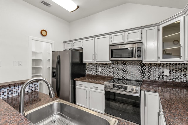3841 Beaumont Ln, Plano, TX 75023 - kitchen featuring appliances with stainless steel finishes, a sink, decorative backsplash, glass insert cabinets, and lofted ceiling