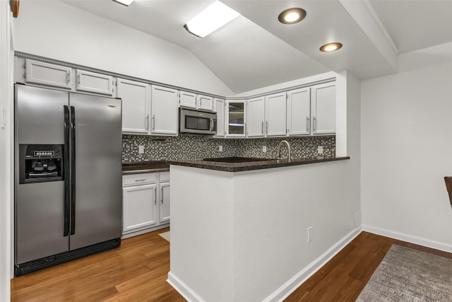 3841 Beaumont Ln, Plano, TX 75023 - kitchen with appliances with stainless steel finishes, dark countertops, decorative backsplash, wood finished floors, and vaulted ceiling
