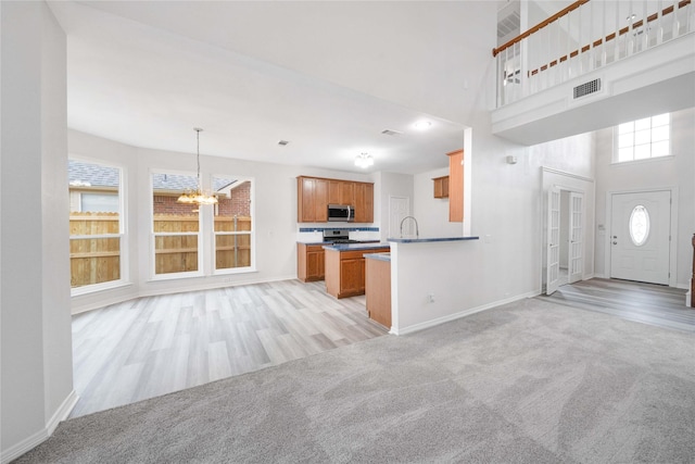kitchen with stainless steel appliances, a chandelier, open floor plan, baseboards, and a towering ceiling