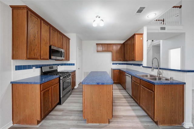 kitchen featuring appliances with stainless steel finishes, a sink, dark countertops, and light wood-style flooring