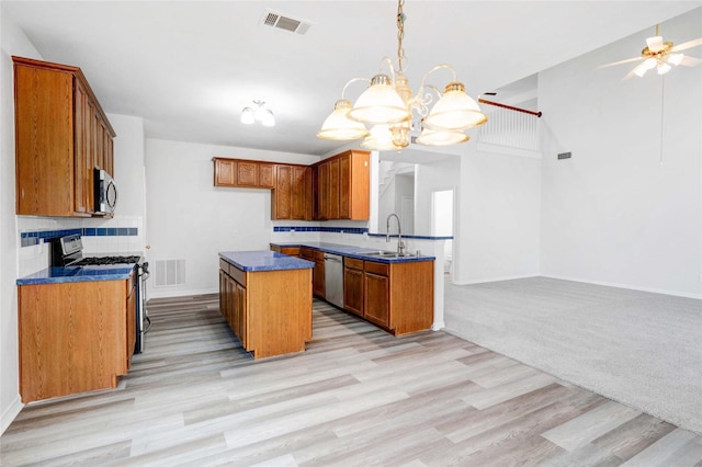 kitchen with stainless steel appliances, a sink, brown cabinets, baseboards, and light wood-style flooring