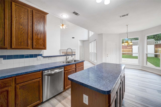 kitchen featuring dishwasher, a sink, dark countertops, and tasteful backsplash