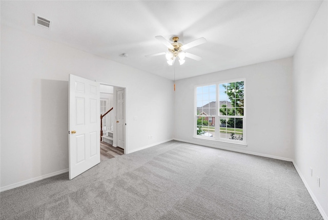 carpeted empty room with ceiling fan and baseboards