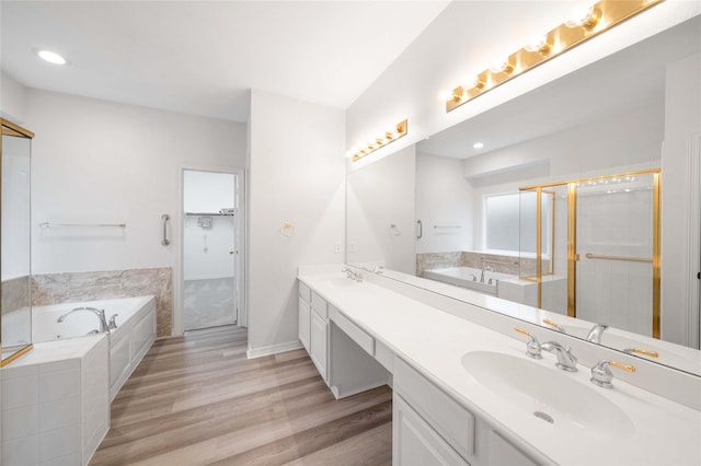 full bath with a garden tub, double vanity, wood finished floors, a spacious closet, and recessed lighting