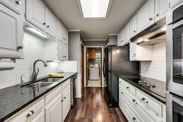 kitchen with a sink, washer / dryer, under cabinet range hood, black appliances, and tasteful backsplash