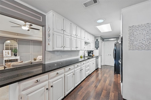kitchen with dishwasher, white cabinetry, dark wood-type flooring, a sink, and decorative backsplash