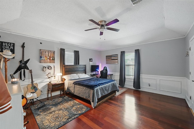 bedroom featuring a textured ceiling, wood finished floors, a wainscoted wall, and ceiling fan