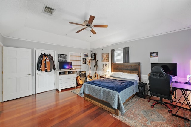 bedroom with wood finished floors, a raised ceiling, and a ceiling fan