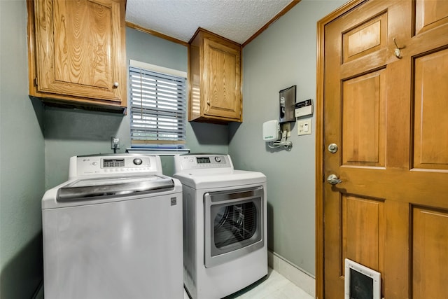 clothes washing area featuring cabinet space, washing machine and clothes dryer, crown molding, and a textured ceiling