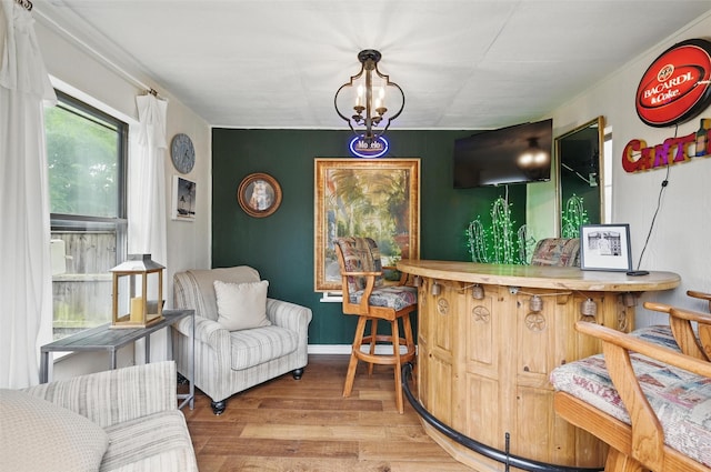 indoor dry bar with wood finished floors, baseboards, and a chandelier