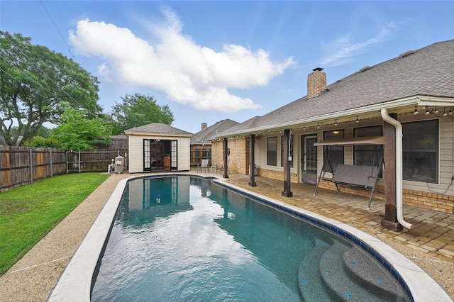 view of pool with an outdoor structure, a patio, and a storage structure