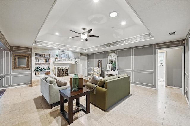 living area featuring a decorative wall, a raised ceiling, a ceiling fan, light tile patterned floors, and recessed lighting