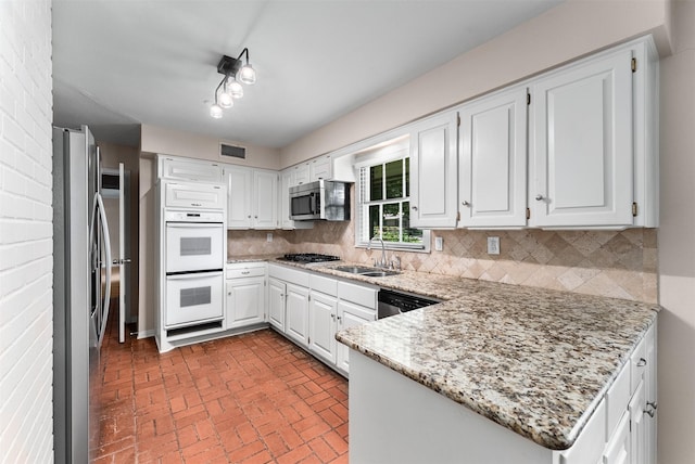 6838 Lupton Dr, Dallas, TX 75225 - kitchen featuring appliances with stainless steel finishes, brick patterned flooring, a sink, tasteful backsplash, and light stone countertops