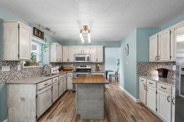 7012 Fox Dr, The Colony, TX 75056 - kitchen featuring stainless steel appliances, a sink, tasteful backsplash, a center island, and a textured ceiling