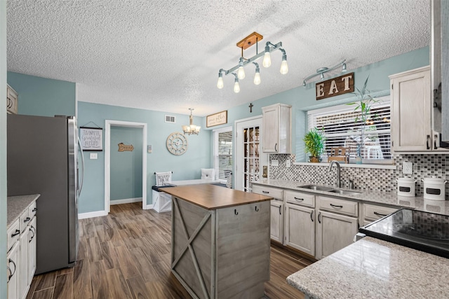 7012 Fox Dr, The Colony, TX 75056 - kitchen featuring freestanding refrigerator, a sink, dark wood-style floors, tasteful backsplash, and a textured ceiling