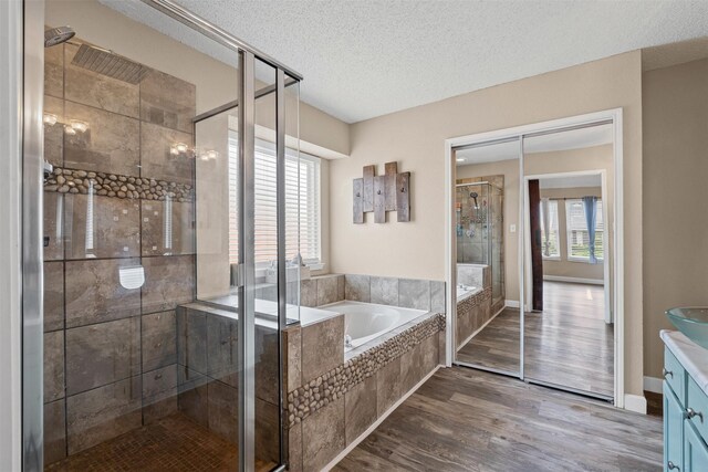 7012 Fox Dr, The Colony, TX 75056 - bathroom with a shower stall, a bath, a textured ceiling, wood finished floors, and vanity