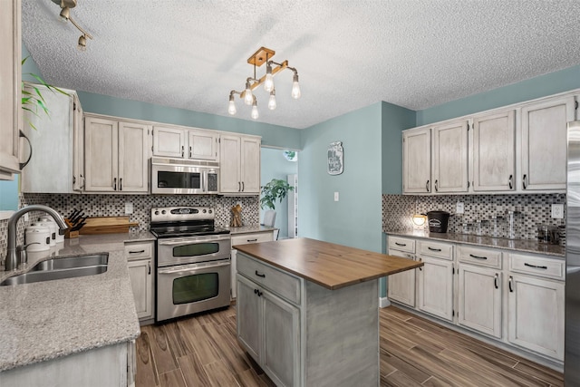 7012 Fox Dr, The Colony, TX 75056 - kitchen with appliances with stainless steel finishes, a sink, dark wood-style flooring, a textured ceiling, and decorative backsplash
