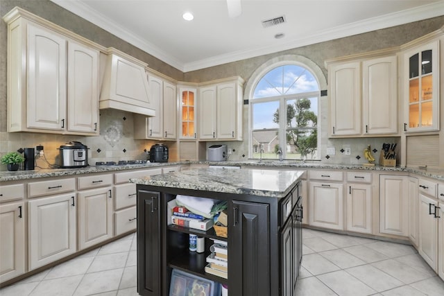 kitchen featuring custom range hood, light tile patterned floors, stainless steel gas stovetop, tasteful backsplash, and ornamental molding