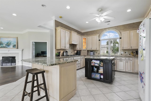 kitchen with custom exhaust hood, a ceiling fan, a kitchen bar, light stone counters, and light tile patterned flooring