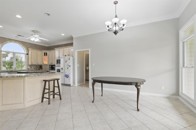 kitchen featuring a chandelier, ornamental molding, baseboards, stainless steel microwave, and hanging light fixtures